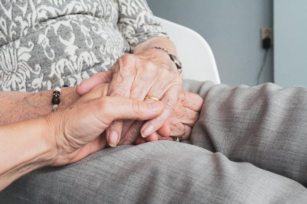 A woman is holding an elderly woman's hand.